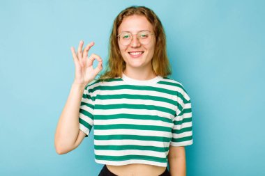 Kafkasyalı genç bir kadın mavi arka planda izole edilmiş neşeli ve kendinden emin..
