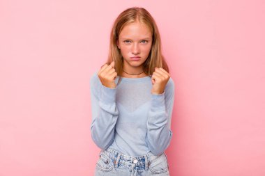 Pembe arka planda izole edilmiş beyaz kız kameraya yumruğunu gösteriyor, agresif yüz ifadesi var..