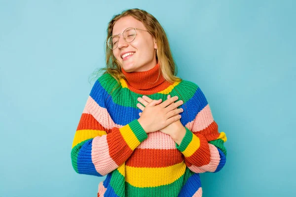 青い背景に孤立した若い白人女性が手を心に留め笑い 幸福の概念 — ストック写真