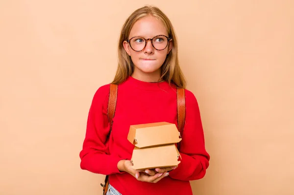 少しCaucasian学生女の子保持ハンバーガー隔離上ベージュ背景混乱 感じている疑問と不確定な — ストック写真