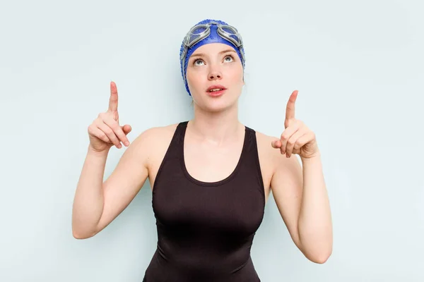 年轻的高加索女子游泳运动员 被隔离在蓝色的背景下 指向上方 张着嘴 — 图库照片