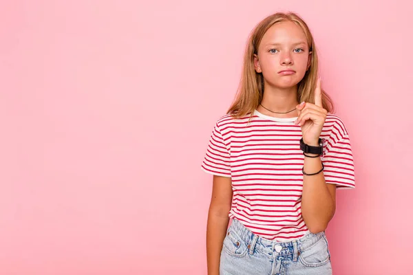 Stock image Caucasian teen girl isolated on pink background showing number one with finger.