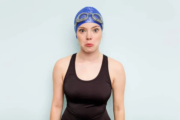 Young Caucasian Swimmer Woman Isolated Blue Background Shrugs Shoulders Open — Stock Photo, Image