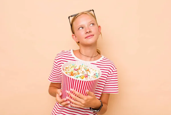 白人小女孩吃米黄色背景的爆米花 — 图库照片