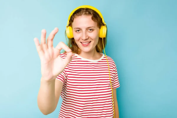 年轻的高加索女人戴着耳机 带着蓝色背景的隔离 快乐而自信地摆出一副不错的姿势 — 图库照片