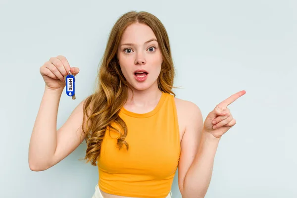 Young Caucasian Woman Holding Home Keys Isolated Blue Background Pointing — Stockfoto