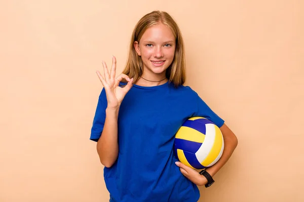 小さいですCaucasian女の子遊びますバレーボール孤立しました上のベージュ背景陽気で自信を持ってショーOkジェスチャー — ストック写真