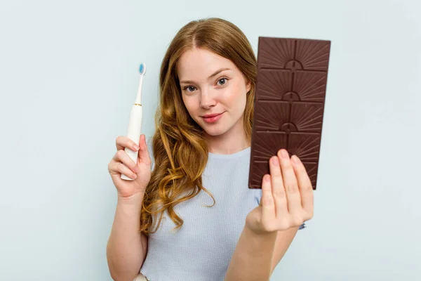 Junge Kaukasische Frau Hält Schokolade Und Zahnbürste Isoliert Auf Blauem — Stockfoto