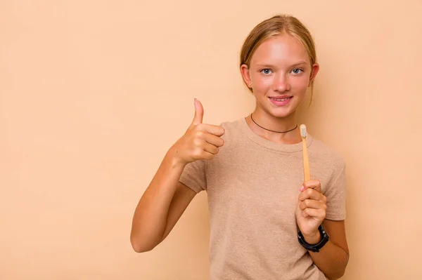 白人少女用米色背景的微笑和竖起大拇指来刷牙 — 图库照片