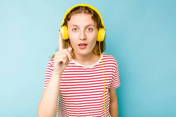 青い背景にヘッドフォンを装着した若い白人女性は アイデア インスピレーションの概念を持っています — ストック写真