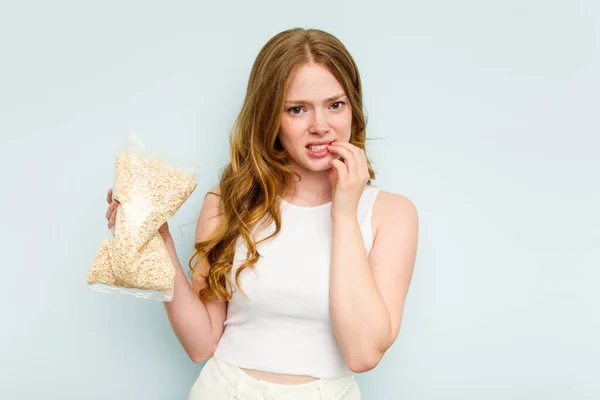 Young Caucasian Woman Holding Oatmeal Isolated Blue Background Biting Fingernails — Stock Photo, Image