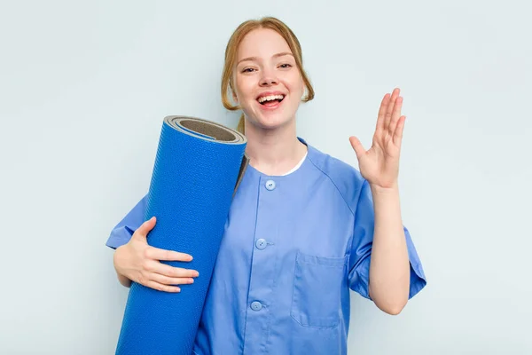 Young Caucasian Physiotherapist Holding Mat Isolated Blue Background Receiving Pleasant — Stock Photo, Image