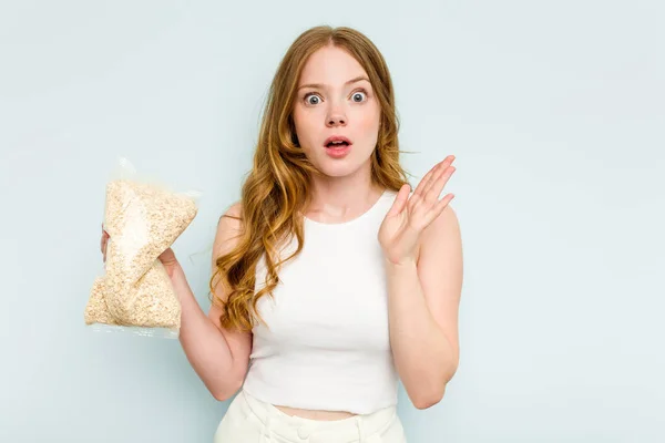 Young Caucasian Woman Holding Oatmeal Isolated Blue Background Surprised Shocked — Stock Photo, Image