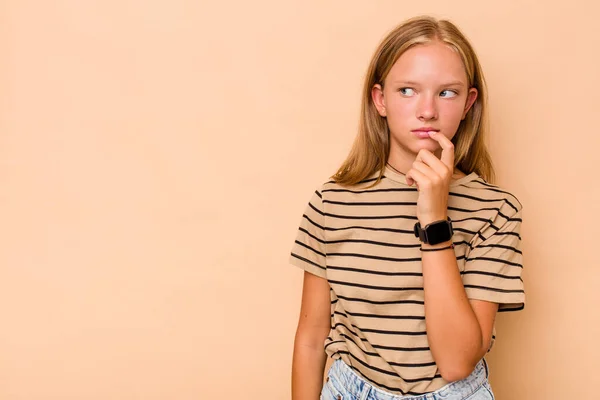 stock image Caucasian teen girl isolated on beige background relaxed thinking about something looking at a copy space.