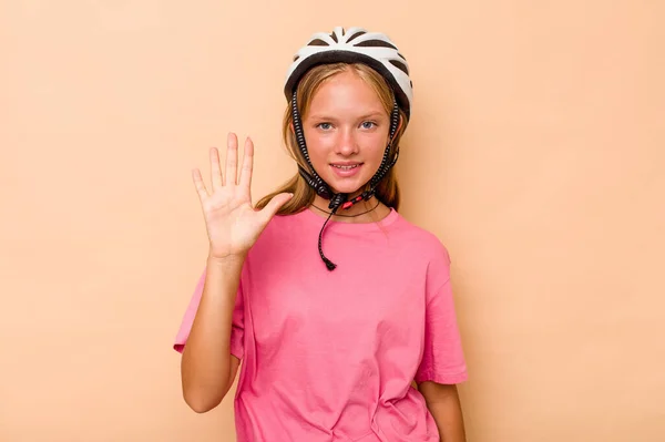 Little caucasian girl wearing a bike helmet isolated on beige background smiling cheerful showing number five with fingers.