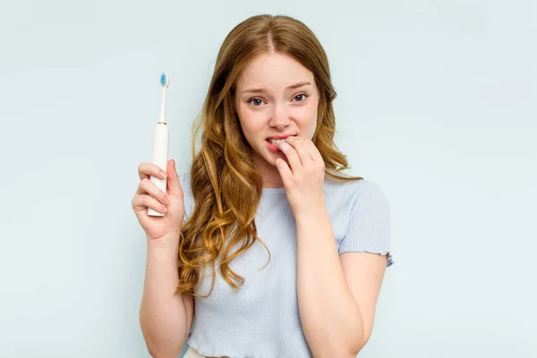 Jonge Blanke Vrouw Met Elektrische Tandenborstel Geïsoleerd Blauwe Achtergrond Bijtende — Stockfoto