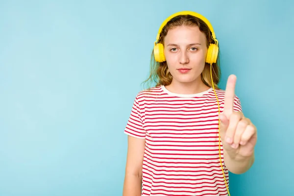 Młoda Kaukaska Kobieta Nosi Słuchawki Odizolowane Niebieskim Tle Pokazując Numer — Zdjęcie stockowe
