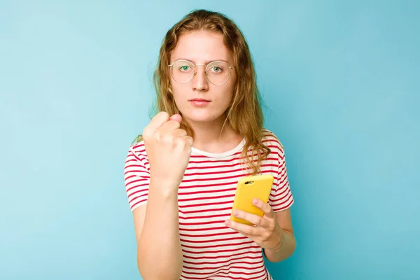 Mladá Běloška Drží Mobilní Telefon Izolovaný Modrém Pozadí Ukazující Pěst — Stock fotografie