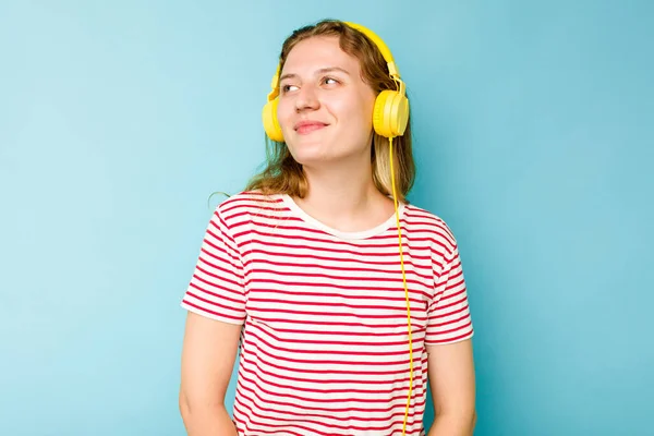 年轻的高加索女人带着耳机 与蓝色背景隔离 梦想着实现自己的目标和目的 — 图库照片