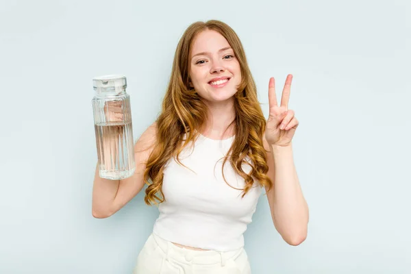 Молодая Белая Женщина Держащая Банку Водой Голубом Фоне Показывает Номер — стоковое фото