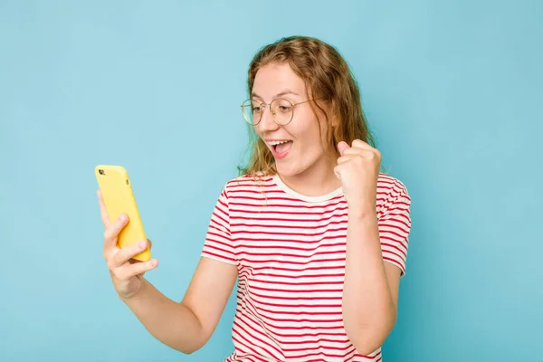 青の背景に隔離された携帯電話を持っている若い白人女性 — ストック写真
