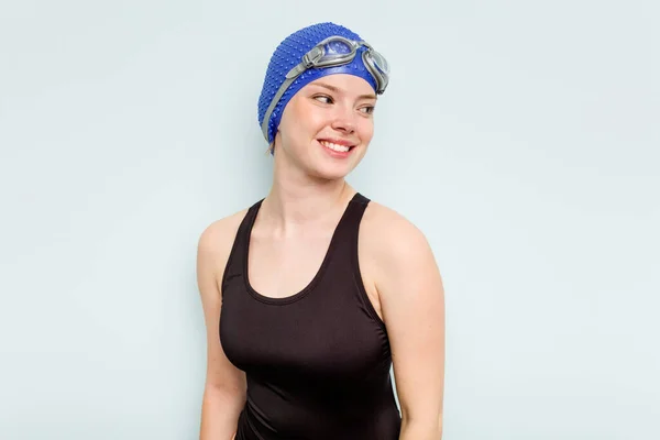 Giovane Donna Nuotatore Caucasico Isolato Sfondo Blu Guarda Parte Sorridente — Foto Stock