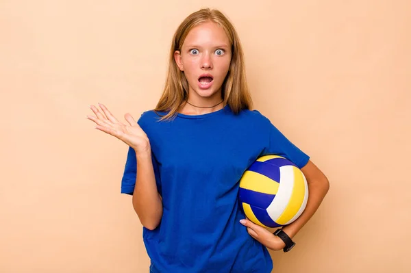 Маленькая Кавказская Девочка Играющая Волейбол Бежевом Фоне Удивлена Шокирована — стоковое фото