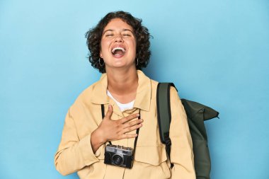 Klasik kameralı genç gezgin kadın elini göğsünde tutarak kahkahalar atıyor..