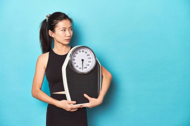 Asyalı sporcu kadın skalayı tutuyor, stüdyo çekimi.