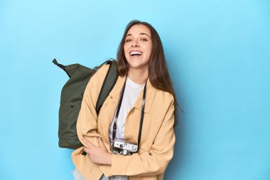 Kameralı ve sırt çantalı genç beyaz kadın gezgin gülüyor ve eğleniyor..