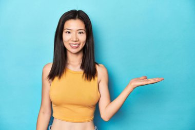 Yazın sarı bluzlu Asyalı bir kadın, stüdyo düzeneği, bir avuç içinde fotokopi alanı ve belinde başka bir el tutan.