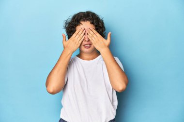 Kısa saçlı, genç, beyaz bir kadın elleriyle gözlerini kapatmaktan korkuyor..