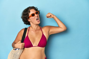 Plaj çantalı genç bir kadın zaferden sonra yumruğunu kaldırıyor, kazanan konsept..