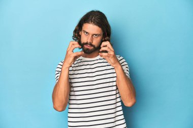 Çizgili gömlekli sakallı adam, mavi arka plan gergin ellerle çığlık atıyor..