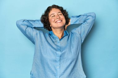 Kısa saçlı, kendine güvenen, elleri başının arkasında olan beyaz bir kadın..