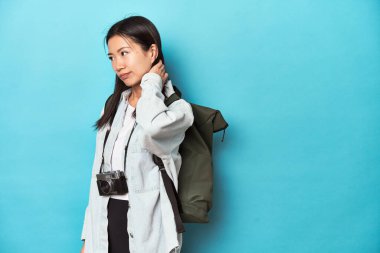 Genç Asyalı gezgin macera yakalamaya hazır, kafasının arkasına dokunuyor, düşünüyor ve bir seçim yapıyor..