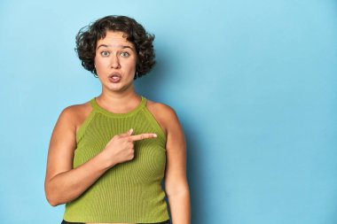 Kafkasyalı genç bir kadın. Kısa saçlı. Yan tarafı işaret ediyor.