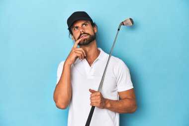 Uzun saçlı golf sopası ve şapkası olan rahat bir şekilde fotokopi odasına bakan bir şey düşünüyor..