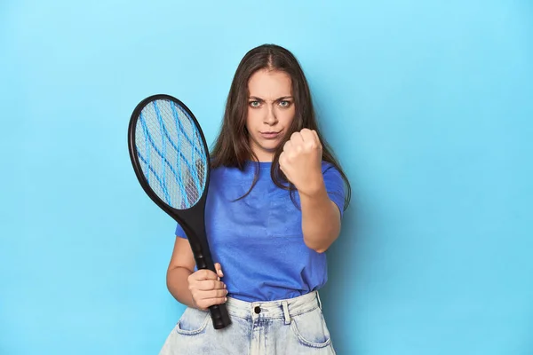 カメラに拳を示す青い背景に電気バグを帯びた女性 積極的な表情 — ストック写真