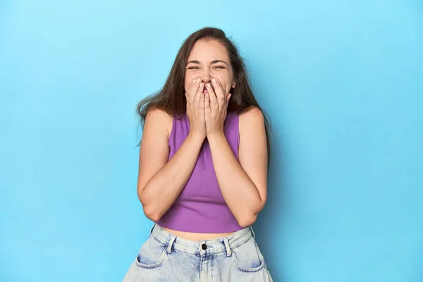 Módní Mladá Žena Purpurovém Tričku Modrém Pozadí Směje Něčemu Zakrývá — Stock fotografie