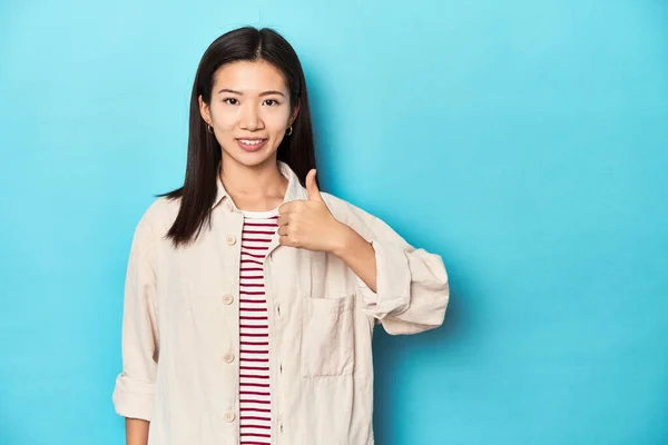 身穿分层衬衫和条纹T恤的亚洲女人 面带微笑 竖起大拇指 — 图库照片