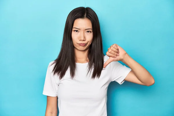 Młoda Azjatka Białej Koszulce Ujęcie Studyjne Opuszczony Kciuk Rozczarowanie Koncepcją — Zdjęcie stockowe