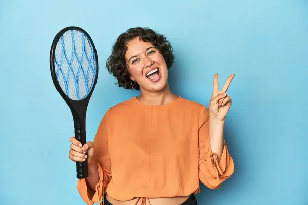 電気蚊ラケットを持つ若い女性 電気蚊ラケット喜びと指の平和のシンボルを示すケアフリー — ストック写真