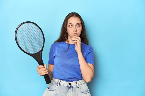 Woman Electric Bug Zapper Blue Background Looking Sideways Doubtful Skeptical — Stock Photo, Image