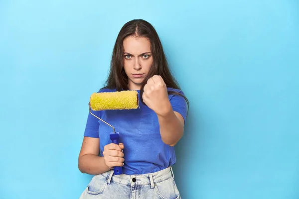 Młoda Kobieta Żółtym Wałkiem Niebieskim Tle Pokazuje Pięść Kamery Agresywny — Zdjęcie stockowe