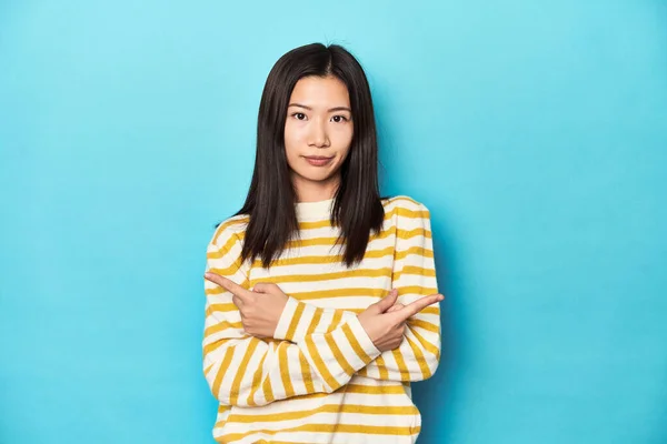 Asian Woman Striped Yellow Sweater Points Sideways Trying Choose Two — Stock Photo, Image