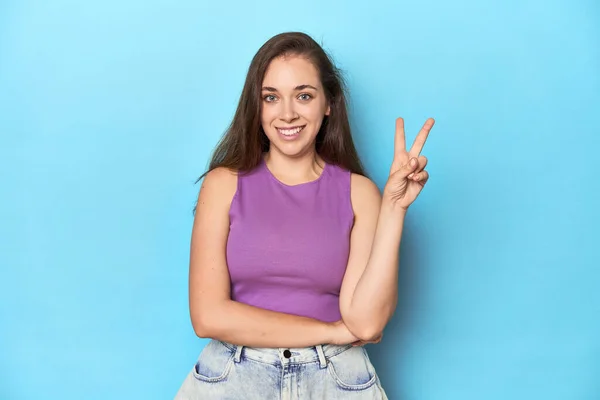 Модна Молода Жінка Фіолетовому Верху Синьому Фоні Показує Номер Два — стокове фото