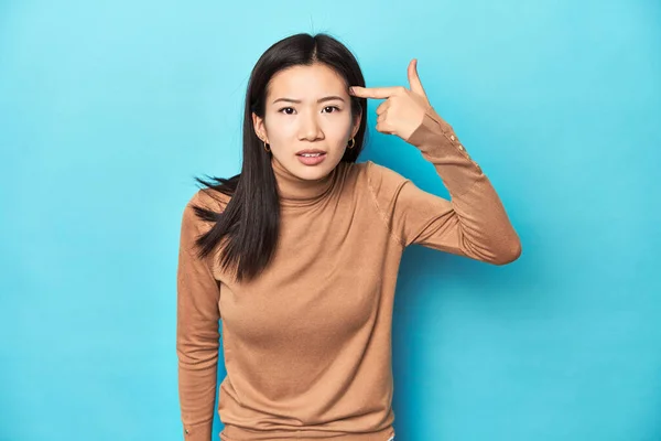 身穿棕色高领毛衣的年轻亚洲女人 用食指表示失望的姿态 — 图库照片