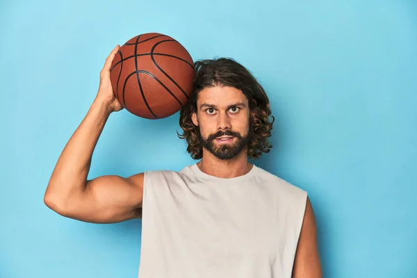 青いスタジオでバスケットボールを持っている長髪のひげ付き男 — ストック写真
