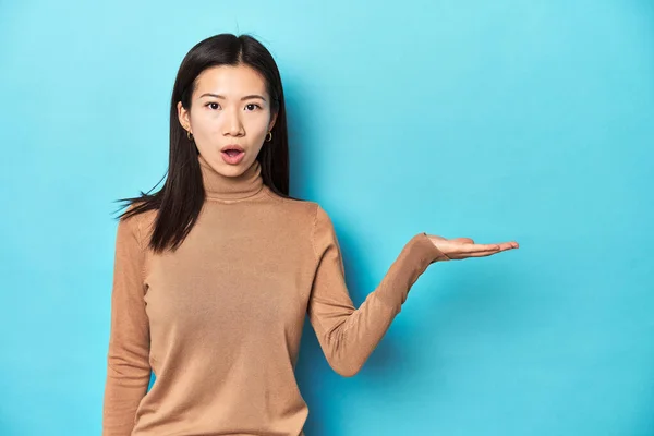 Young Asian Woman Brown Turtleneck Impressed Holding Copy Space Palm — Stock Photo, Image